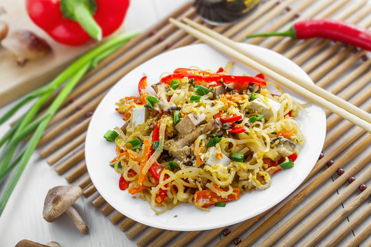 Asian food. Fried rice noodles with tofu, vegetables and shiitake mushroom. Oriental cuisine meal.