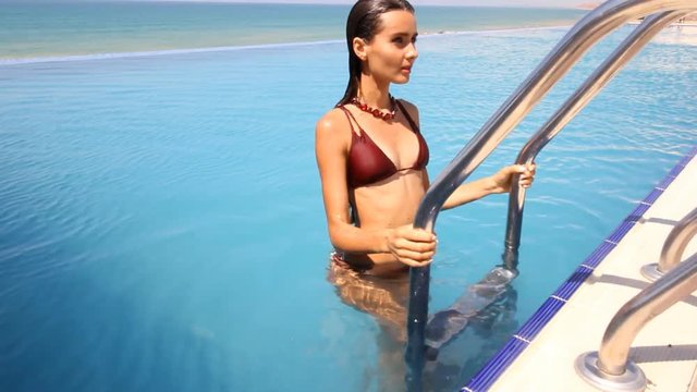 girl swims in a pool in a beautiful bathing suit near the sea