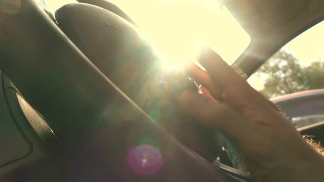 Happy driver drumming his fingers on the steering wheel against blazing sun, warm colors. 4K video