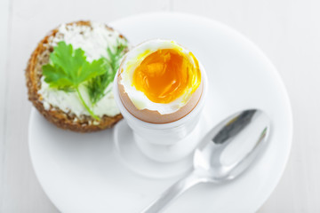 Perfect soft boiled egg, open bread sandwich with butter and cup of coffee on a table. Traditional food for healthy breakfast. Top view.