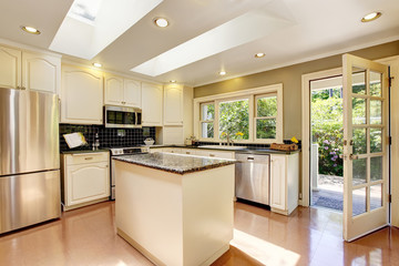 White kitchen with granite tops. Kitchen island and tile floor.