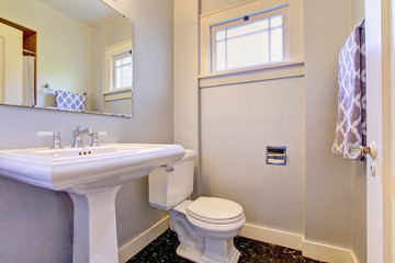 Bathroom interior in light purple tones with dark marble tile floor.