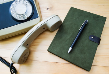 Notebook with a pencil eraser and put on wood antique phone.