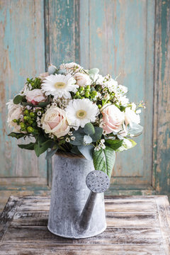 Bouquet of pink roses and white gerbera flowers in grey watering