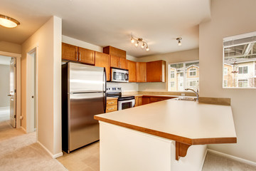 Empty kitchen room interior with wooden cabinets and tile floor.