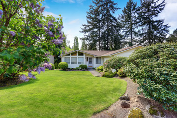 American house with siding trim and well kept lawn around.