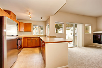 Empty kitchen room interior with wooden cabinets and tile floor.