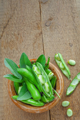 Bowl of fresh podded broad beans on a wooden table. Healthy organic food. Top view.