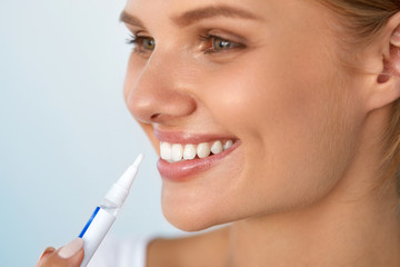 Healthy White Teeth. Beautiful Smiling Woman Using Whitening Pen. High Resolution Image