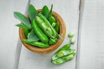 Fresh podded broad been in a bowl. Healthy highly nutrition organic raw food on a table. Top view.