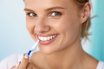 Healthy White Teeth. Beautiful Smiling Woman Using Whitening Pen. High Resolution Image