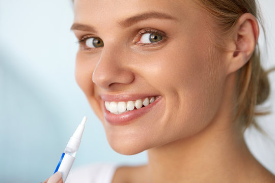Healthy White Teeth. Beautiful Smiling Woman Using Whitening Pen. High Resolution Image