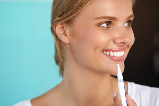Woman With Beautiful Smile, Healthy Teeth Using Whitening Pen. High Resolution Image