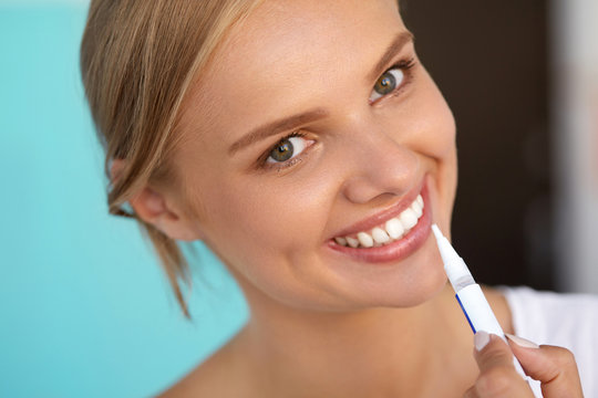 Woman With Beautiful Smile, Healthy Teeth Using Whitening Pen. High Resolution Image