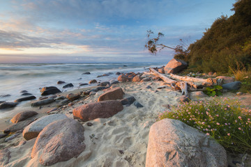 Sea landscape at sunset, sandy beach and cliff,waves breaking on the shore


