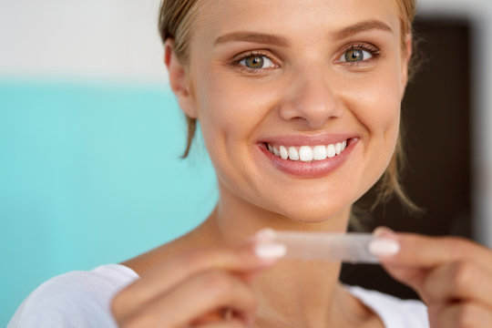 Woman With Healthy White Teeth Using Teeth Whitening Strip. High Resolution Image