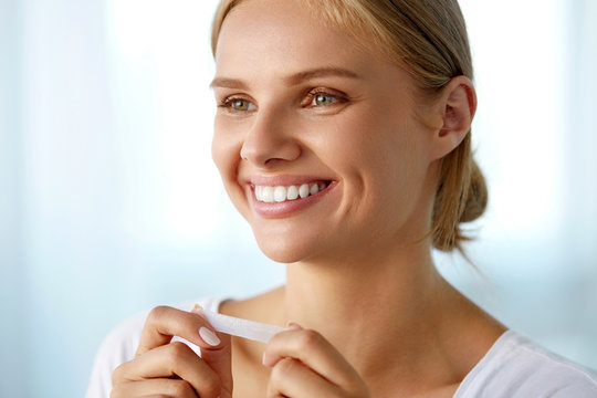 Woman Using Teeth Whitening Strip For Beautiful White Smile. High Resolution Image
