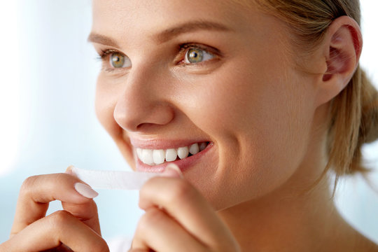 Woman Using Teeth Whitening Strip For Beautiful White Smile. High Resolution Image
