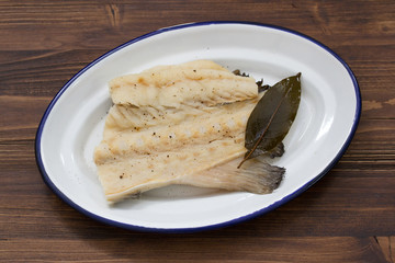 boiled cod fish on white dish on wooden background