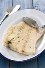 boiled cod fish on white dish on wooden background