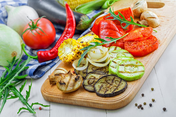 Grilled tomato, corn, eggplant, mushroom, bell pepper, marrow and onion on a table. Healthy prepared food with ingredients.