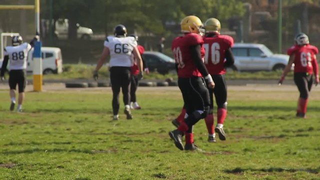 Active American football players changing field sides during game, amateur match