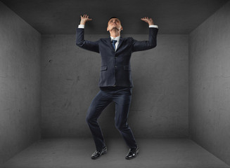 Businessman striving to escape from a small room