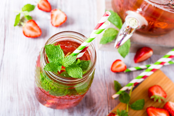 Homemade delicious strawberry compote in glass jar on white wooden table. Healthy food concept. View from above.