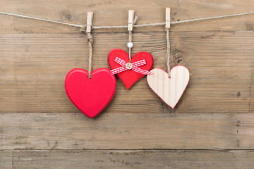 Wooden hearts hanging on a clothesline with clothespins.