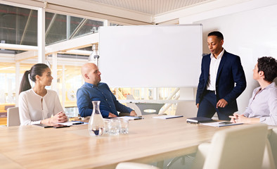 Chairman of a company taking a seat on the end of the conference table in the board room, about to...