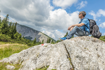 hiker resting on a stone formation on Rax mountain Austria
