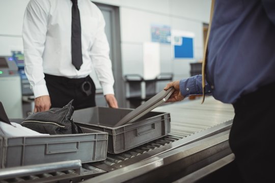 Man putting laptop into tray for security check