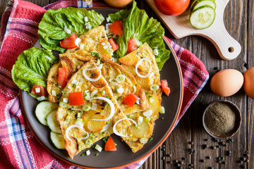 Typical Spanish tortilla - omelet with potatoes and onion with vegetable garnish