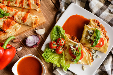 Pancakes stuffed with Bolognese filling - minced beef, pepper, onion, garlic and basil with tomato sauce