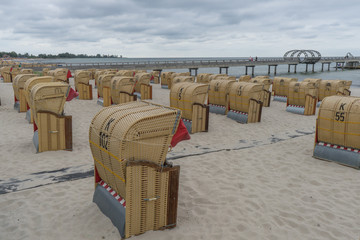 Strandkörbe am Sandstrand mit Seebrücke und Meer im Hintergrund