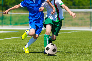 Obraz premium young boys playing football soccer game. Running players in blue and white uniforms