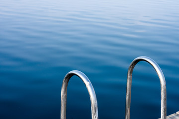 Blue ocean view from a dock with a metal railing
