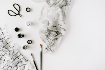 Watercolor, scissors, textile and brushes at white background. Flat lay, top view