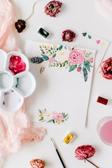 Workspace. Pink and red roses painted with watercolor, paintbrush and roses on white wooden background. Overhead view. Flat lay, top view
