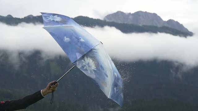 A person opens umbrella and raindrops fly away