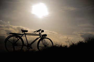 Naklejka na ściany i meble silhouette of a retro bicycle. parked in a meadow in evening, th