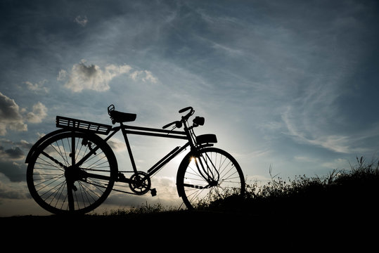 silhouette of a retro bicycle. parked in a meadow in evening, th
