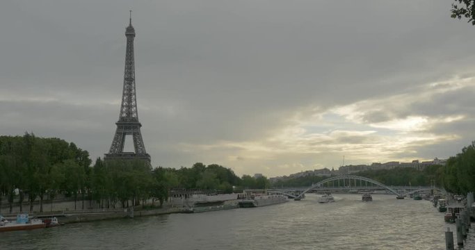 PARIS, FRANCE - SEPTEMBER 06, 2015: Timelapse shot of touristic ships sailing on Seine River with Eiffel Tower on its bank