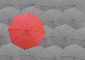 Red umbrella on the top of gray umbrellas background.