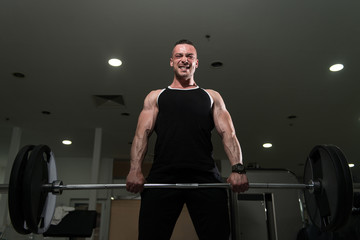 Fototapeta na wymiar Muscular Man Exercising Back With Barbell In Gym