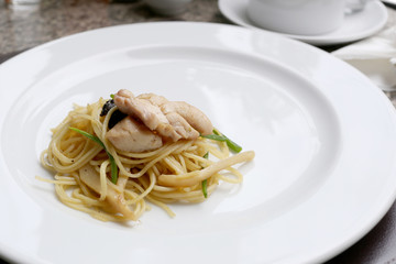 Puff yellow noodles with chicken meat on white dish.
