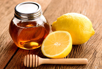 Jars of honey with lemons on wooden table