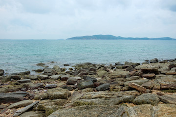 Rocks on shoreline with sea and mountain background