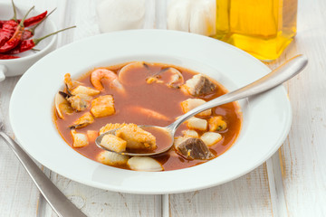 delicious plate of seafood soup with spoon in wooden table