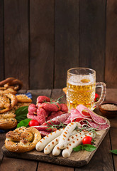 Glass of beer, pretzels and various sausages on wooden background. Oktoberfest.